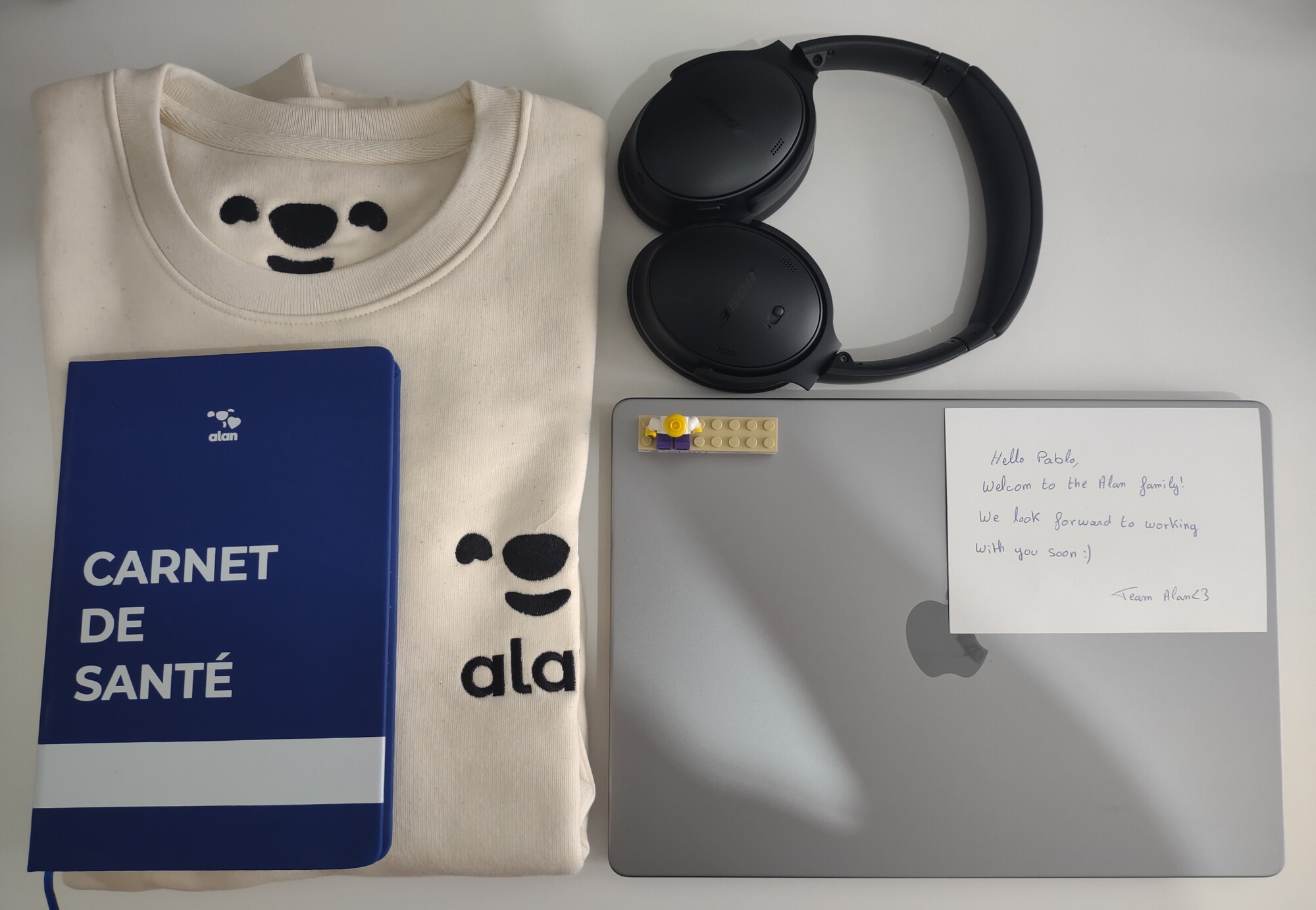 Welcome pack de Alan: mac, cascos, cuaderno, sudadero, lego y carta de bienvenida.